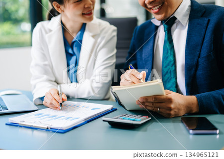Business documents on office table with smart phone and calculator digital tablet and graph business with social network diagram and two colleagues discussing data Business documents on office table with smart phone and calculator digital tablet and graph business with social network diagram and two colleagues discussing data 134965121