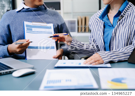 Business documents on office table with smart phone and calculator digital tablet and graph business with social network diagram and two colleagues discussing data working in the office 134965227