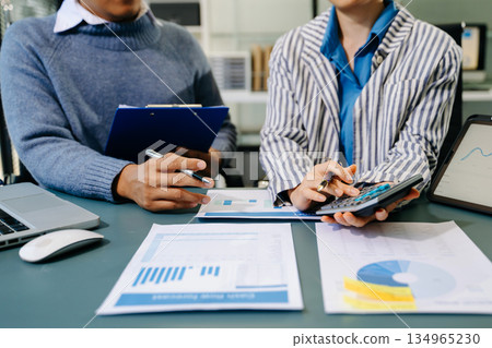 Business documents on office table with smart phone and calculator digital tablet and graph business with social network diagram and two colleagues discussing data working in the office 134965230