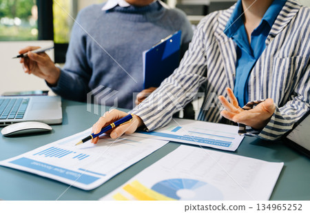 Business documents on office table with smart phone and calculator digital tablet and graph business with social network diagram and two colleagues discussing data working in the office 134965252