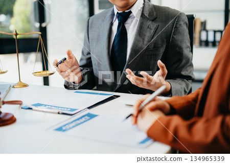 Lawyer consulting client with legal documents and scales of justice on desk. Concept of law, contract, consultation, and professional legal service. Lawyer consulting client with legal documents and scales of justice on desk. Concept of law, contract, consultation, and professional legal service. 134965339