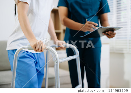 Healthcare professional assisting a patient in physiotherapy rehab using a walker, symbolizing recovery, mobility support, 134965399