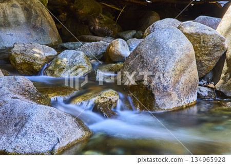 Smooth River Rocks and Flowing Water with Sunlight in Natural Forest Setting Smooth River Rocks and Flowing Water with Sunlight in Natural Forest Setting 134965928
