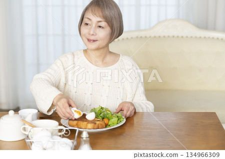 Senior woman eating boiled eggs Senior woman eating boiled eggs 134966309