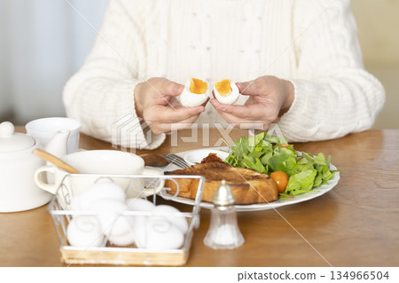 Senior woman eating boiled egg out of focus 134966504