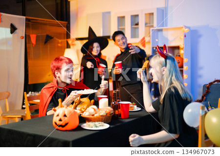 Joyful office Halloween party with coworkers in costumes, celebrating with drinks and laughter, fostering teamwork and festive spirit 134967073