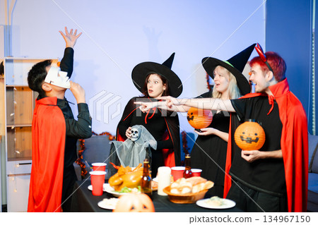 Halloween party react with surprise and laughter to spooky props like pumpkins and a ghost skeleton. Perfect seasonal fun, decor, and festive vibes. Halloween party react with surprise and laughter to spooky props like pumpkins and a ghost skeleton. Perfect seasonal fun, decor, and festive vibes. 134967150