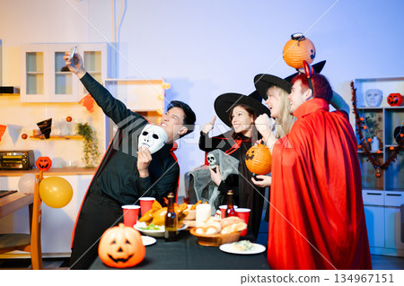 Halloween party react with surprise and laughter to spooky props like pumpkins and a ghost skeleton. Perfect seasonal fun, decor, and festive vibes. 134967151
