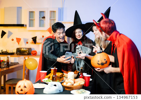 Halloween party react with surprise and laughter to spooky props like pumpkins and a ghost skeleton. Perfect seasonal fun, decor, and festive vibes. 134967153