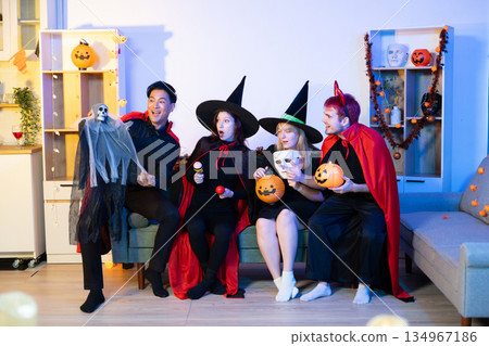 Joyful office Halloween party with coworkers in costumes, celebrating with drinks and laughter, fostering teamwork and festive spirit 134967186