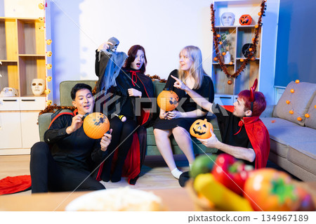 Halloween costumes toast with red wine at a festive indoor party. Pumpkins, food, and celebration set the mood for fun, spooky vibes and seasonal cheer. Halloween costumes toast with red wine at a festive indoor party. Pumpkins, food, and celebration set the mood for fun, spooky vibes and seasonal cheer. 134967189