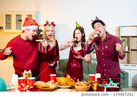 Group of friends celebrating Christmas together at home, sharing food and joy. Festive holiday lifestyle, warm atmosphere, friendship, and cheerful Christmas party 134967262