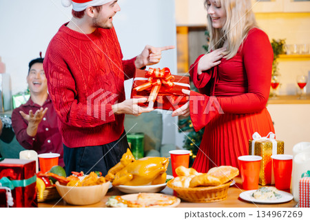 Friends celebrating Christmas together at a cozy home party with gift exchange, festive food and joyful holiday atmosphere. Friends celebrating Christmas together at a cozy home party with gift exchange, festive food and joyful holiday atmosphere. 134967269