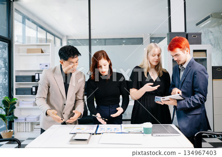 Happy businesspeople while collaborating on a new project in an office. Group of diverse businesspeople using a laptop and tablet in office. 134967403