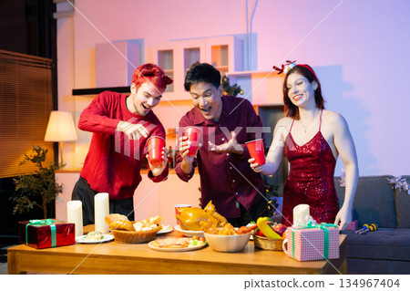 Friends celebrate Christmas with gift exchanges, festive food, and perfect scene for holiday and New Year themes filled with joy and togetherness 134967404