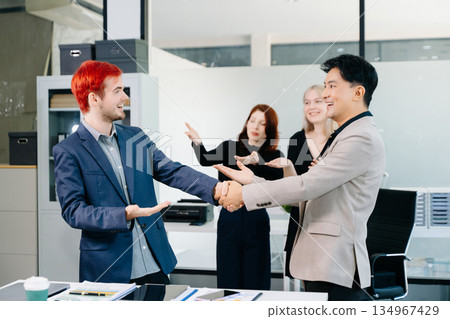 Successful business handshake with colleagues applauding, symbolizing teamwork, partnership, trust, and corporate achievement in a modern office 134967429
