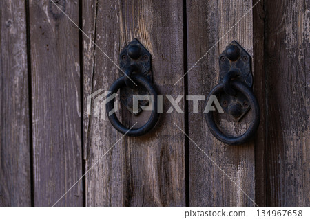 Metal handles on the old wooden door background Metal handles on the old wooden door background 134967658