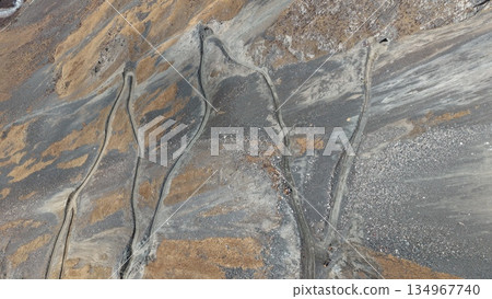 Aerial view of winding dirt roads through rocky mountainous terrain Aerial view of winding dirt roads through rocky mountainous terrain 134967740