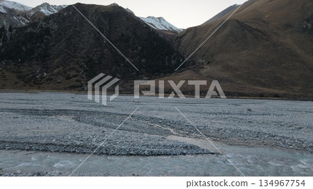 Serene river winding through rocky landscape with majestic mountains Serene river winding through rocky landscape with majestic mountains 134967754