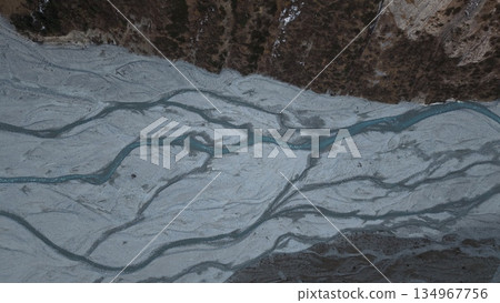 Aerial view of winding river flowing through rocky terrain landscape Aerial view of winding river flowing through rocky terrain landscape 134967756