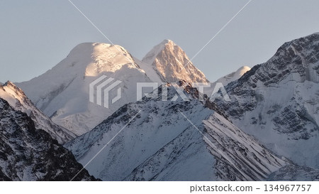Majestic snow-capped mountains under soft morning light with clear sky Majestic snow-capped mountains under soft morning light with clear sky 134967757