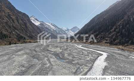 Majestic mountain landscape with riverbed and snow-capped peaks Majestic mountain landscape with riverbed and snow-capped peaks 134967776