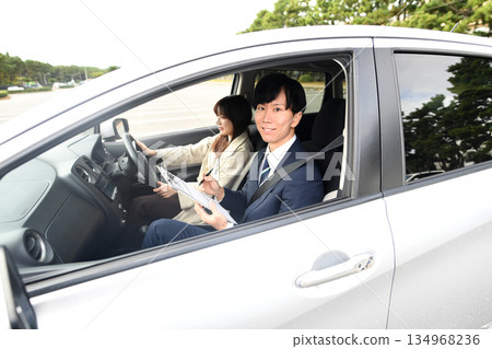 Asian male instructor and young woman teaching at driving school 134968236