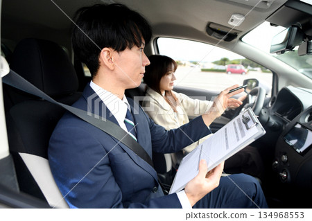Asian male instructor and young woman teaching at driving school Asian male instructor and young woman teaching at driving school 134968553