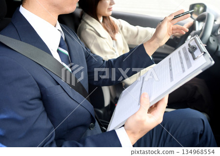 Asian male instructor and young woman teaching at driving school Asian male instructor and young woman teaching at driving school 134968554