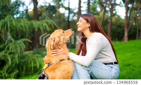 Woman smiling bonding with her golden retriever dog in park Woman smiling bonding with her golden retriever dog in park 134968558