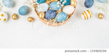 Easter eggs in blue and gold colors in wooden bowl with copy space on white background 134969298