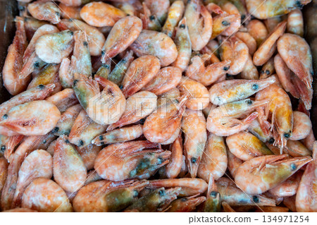 A large pile of frozen shrimp with orange-pink shells and frosty coating, ready for market or kitchen use 134971254