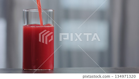 pour red orange juice into glass on concrete countertop with copy space 134971320