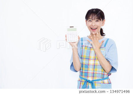 A housewife smiling and surprised while holding a calculator A housewife smiling and surprised while holding a calculator 134971496