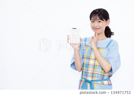 A housewife thinking with a smile while holding a calculator 134971752