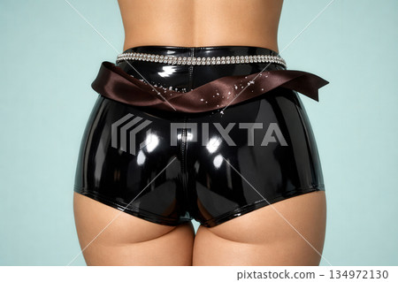 High Waist Shiny Black Latex Shorts With Diamond Belt And Brown Silk Ribbon On Blue Background High Waist Shiny Black Latex Shorts With Diamond Belt And Brown Silk Ribbon On Blue Background 134972130
