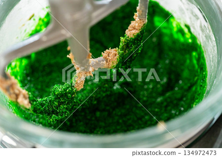 The vibrant green dough mixture for Vibrant Green Gingerbread Cookies for Festive Baking is starting to form, combining butter, sugar, and the green-tinted maple syrup in a mixer. The vibrant green dough mixture for Vibrant Green Gingerbread Cookies for Festive Baking is starting to form, combining butter, sugar, and the green-tinted maple syrup in a mixer. 134972473