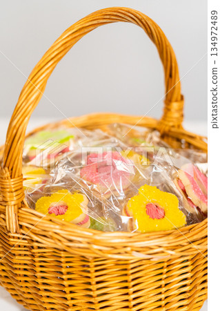 Close-up of a yellow flower-shaped Easter Cookie Sandwich with Raspberry Buttercream in clear wrap, nestled in a rustic basket. A vibrant and cheerful springtime dessert presentation. Close-up of a yellow flower-shaped Easter Cookie Sandwich with Raspberry Buttercream in clear wrap, nestled in a rustic basket. A vibrant and cheerful springtime dessert presentation. 134972489