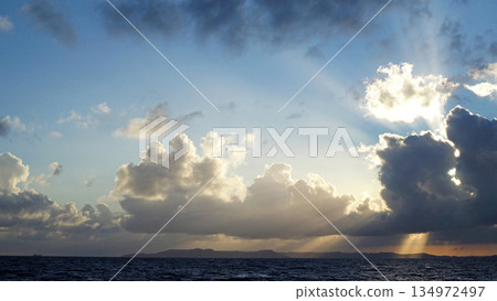 陽光透過雲層灑在沖繩平靜的海面上。 陽光透過雲層灑在沖繩平靜的海面上。 134972497