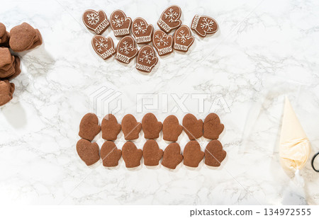Rows of both decorated and plain mitten cookies are arranged together, highlighting the transition from unadorned to beautifully iced holiday cookies. Rows of both decorated and plain mitten cookies are arranged together, highlighting the transition from unadorned to beautifully iced holiday cookies. 134972555