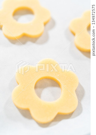 Top view of a baking sheet lined with unbaked flower-shaped sugar cookies. These will form the base for Easter Cookie Sandwich with Raspberry Buttercream. 134972575