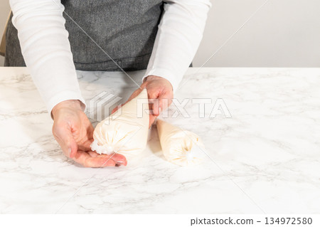 Two piping bags filled with Simple White Royal Icing placed on a marble countertop, ready for use in decorating cookies and other desserts. Two piping bags filled with Simple White Royal Icing placed on a marble countertop, ready for use in decorating cookies and other desserts. 134972580