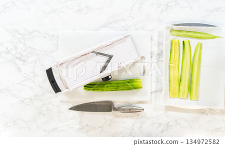 Freshly sliced cucumber laid out on paper towels for moisture removal, part of the Mini Cucumber Sandwiches recipe. Ideal for food prep illustrations or healthy snack tutorials. Freshly sliced cucumber laid out on paper towels for moisture removal, part of the Mini Cucumber Sandwiches recipe. Ideal for food prep illustrations or healthy snack tutorials. 134972582