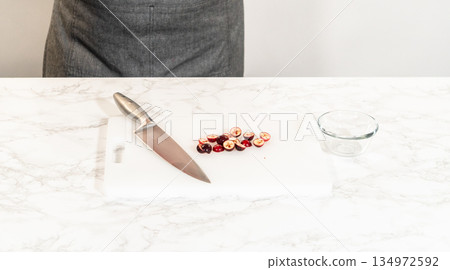 Fresh cranberries are finely chopped on a cutting board, prepared for adding to the cranberry buttercream in the lemon spritz cookie recipe. 134972592