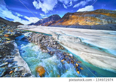 Athabasca Glacier Meltwater Stream and Mountain Landscape Under Blue Sky 134972974