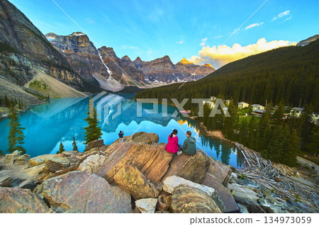 Lake Moraine Sunrise with Tourists Overlooking Blue Water and Mountain Peaks Lake Moraine Sunrise with Tourists Overlooking Blue Water and Mountain Peaks 134973059