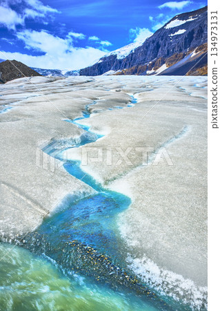 Glacial Meltwater Streams Flowing Across Athabasca Glacier with Majestic Mountain Scenery 134973131