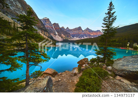 Lake Moraine Sunrise Reflection with Blue Water Pine Trees and Mountain Peaks Lake Moraine Sunrise Reflection with Blue Water Pine Trees and Mountain Peaks 134973137