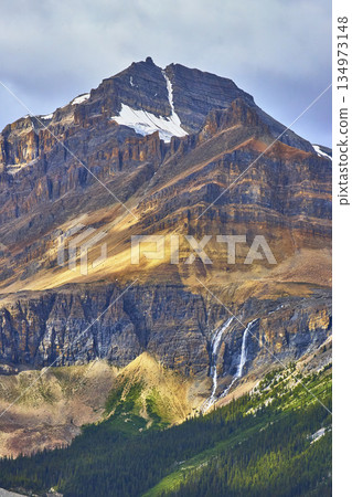 Rocky Mountain Peak Glacier Patch and Waterfall in Lush Forest Landscape Rocky Mountain Peak Glacier Patch and Waterfall in Lush Forest Landscape 134973148