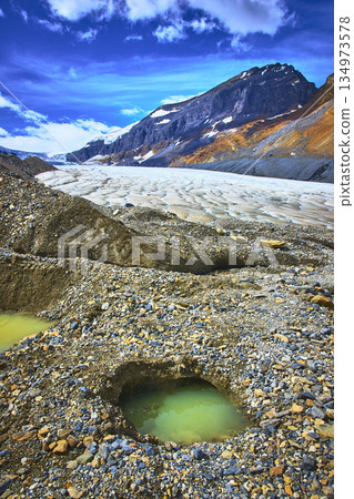 Athabasca Glacier Meltwater Pools and Rocky Mountain Landscape Under Blue Sky 134973578
